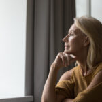 woman looking out window thinking 1720105479 hero