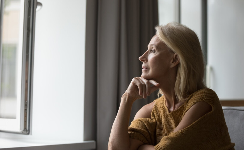 woman looking out window thinking 1720105479 hero